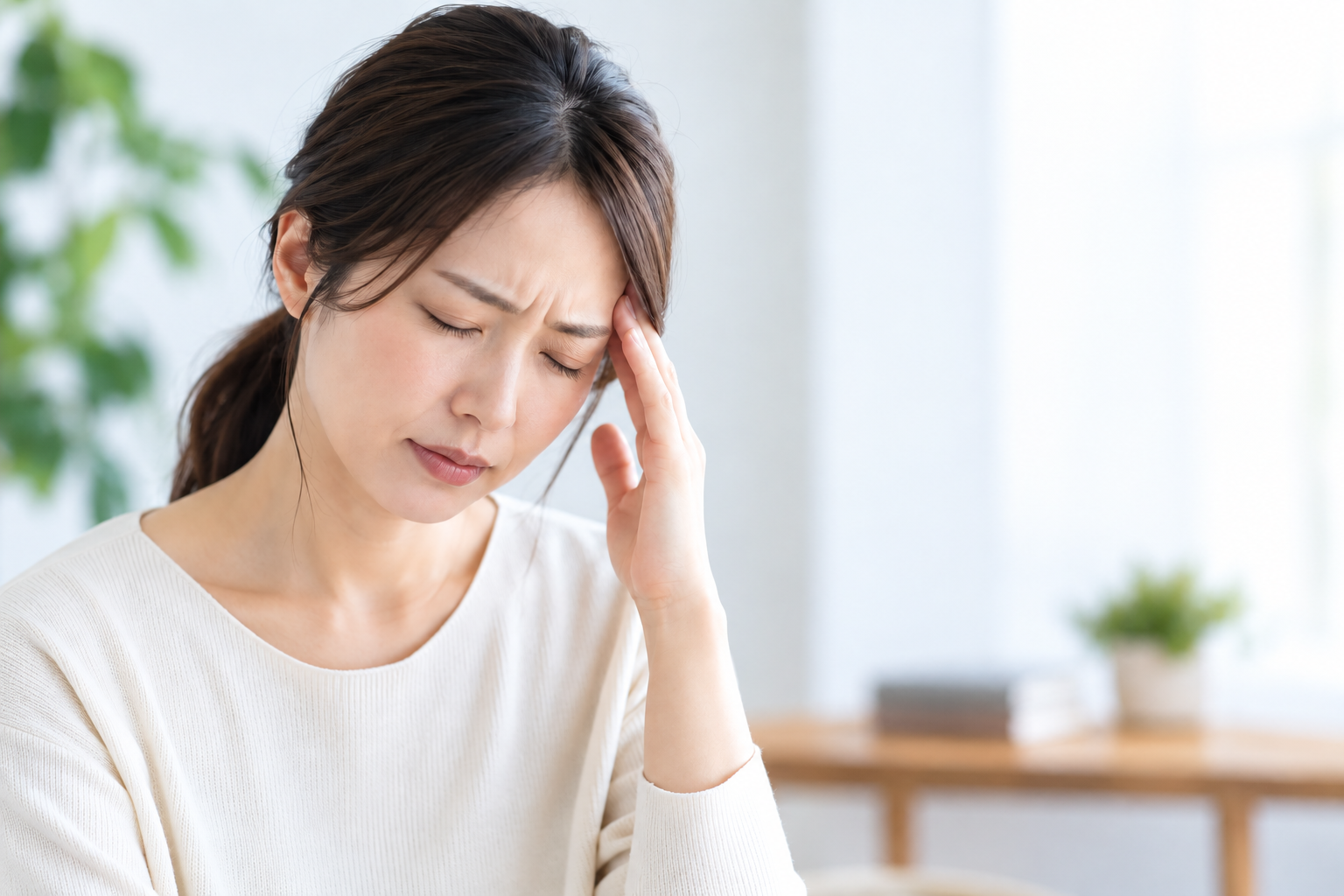 頭痛でこめかみを押さえる女性