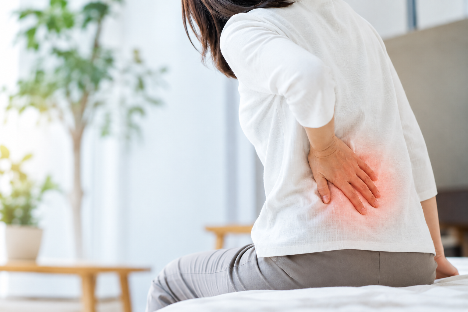 腰痛で腰を押さえる女性